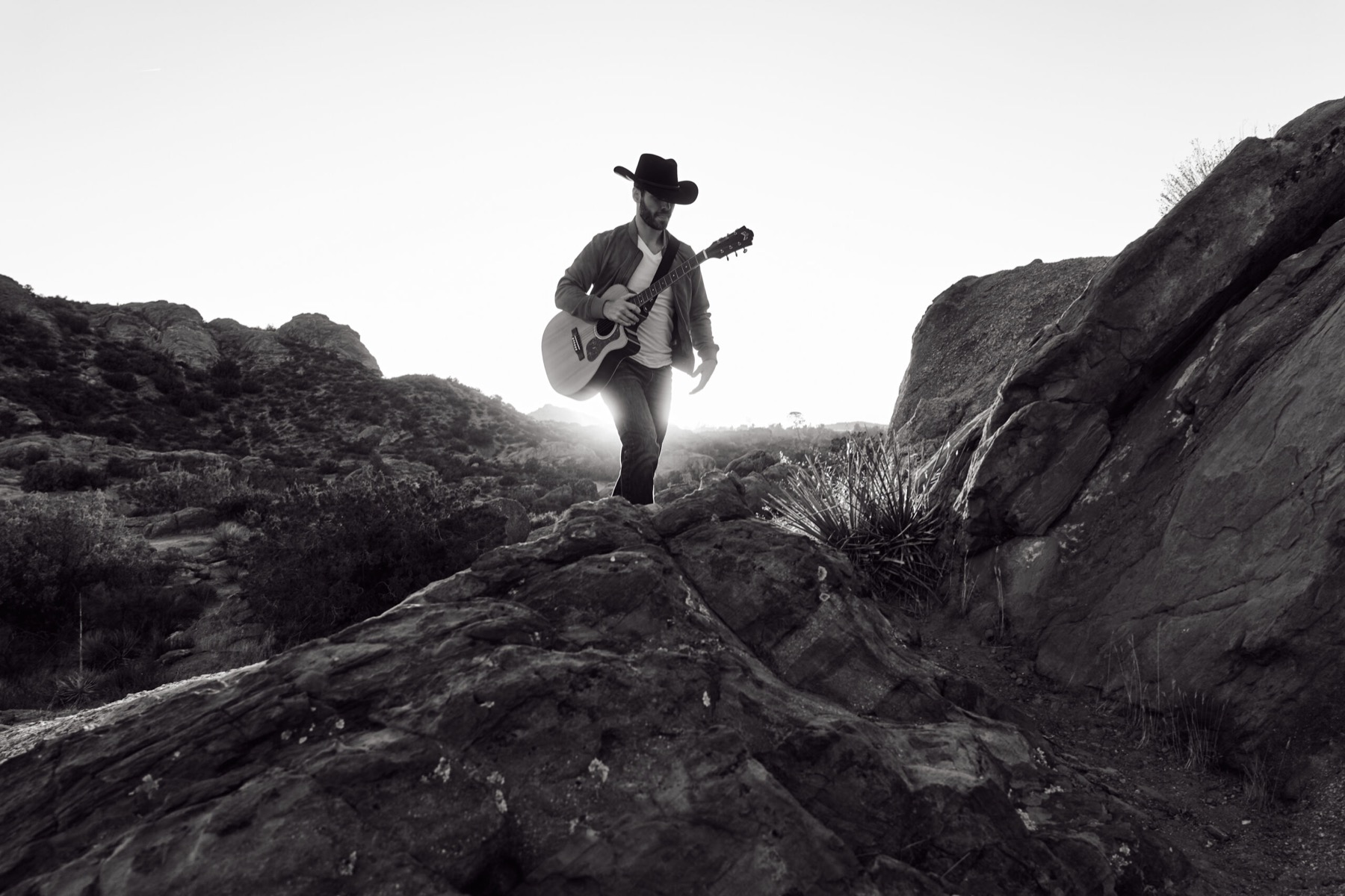 Luke David Carlsen with guitar in the high desert at sundown